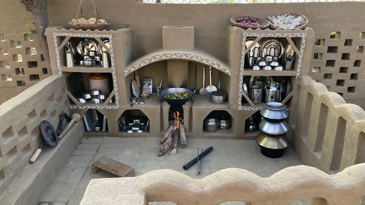 Traditional mud courtyard kitchen with chulha, brass utensils and mandana detailing